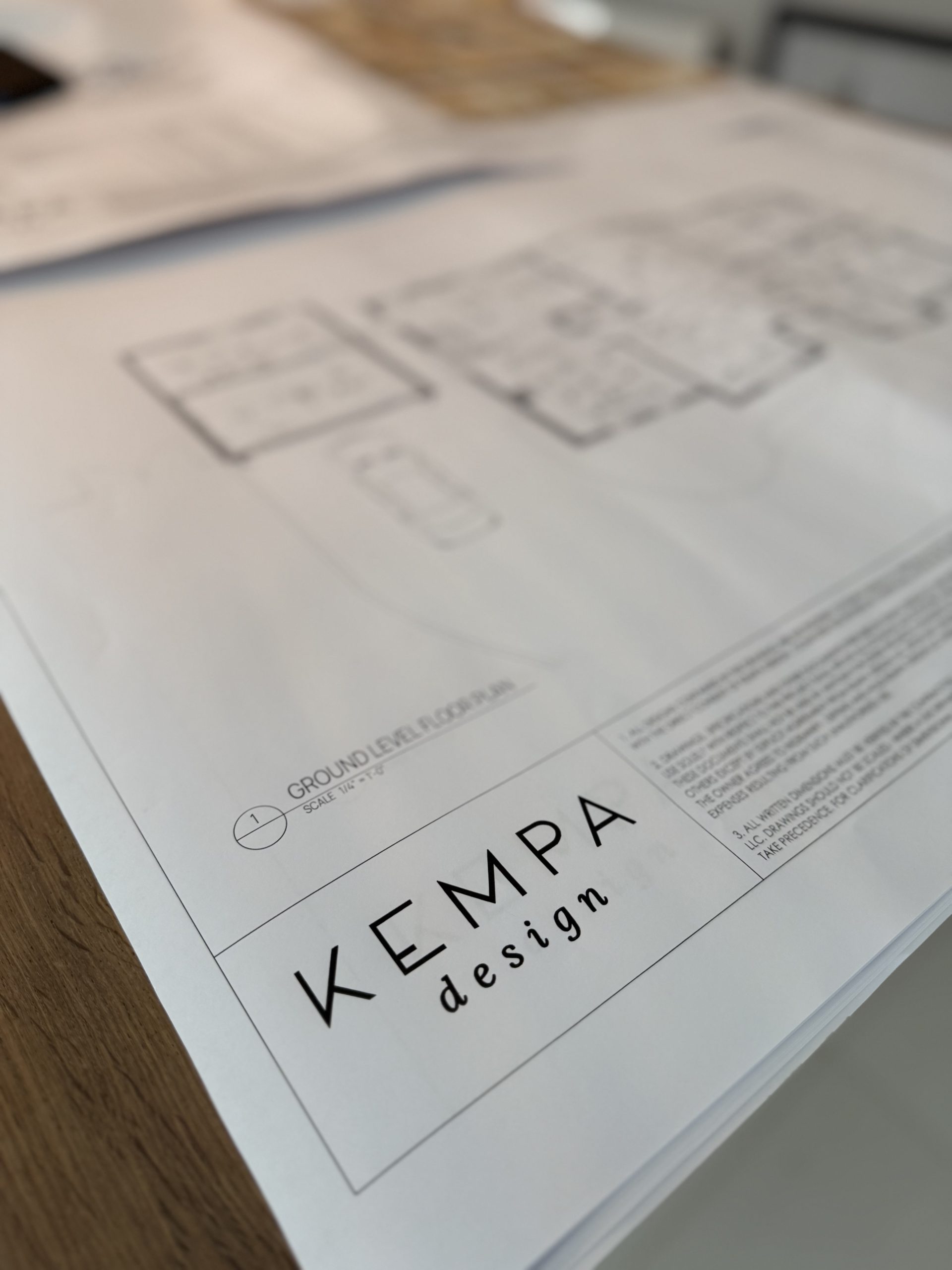 Architectural floor plan on a desk with KEMPA design logo in the title block, labelled Ground Level Floor Plan.